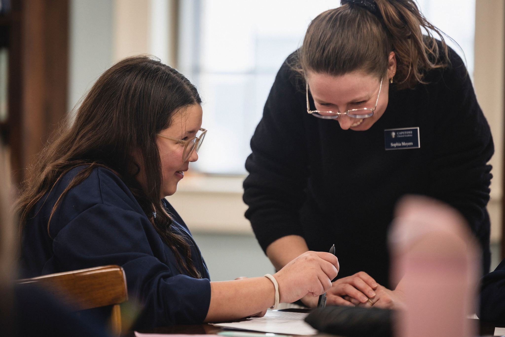 teacher helping girl at desk